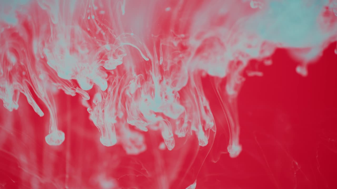 Blue Ink and Paint Dropping into A Water Tank on a Red Background