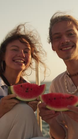 happy couple eating watermelon on a boat