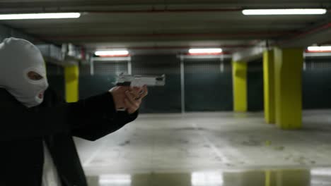 man in a suite with a white mask pointing a gun to the side