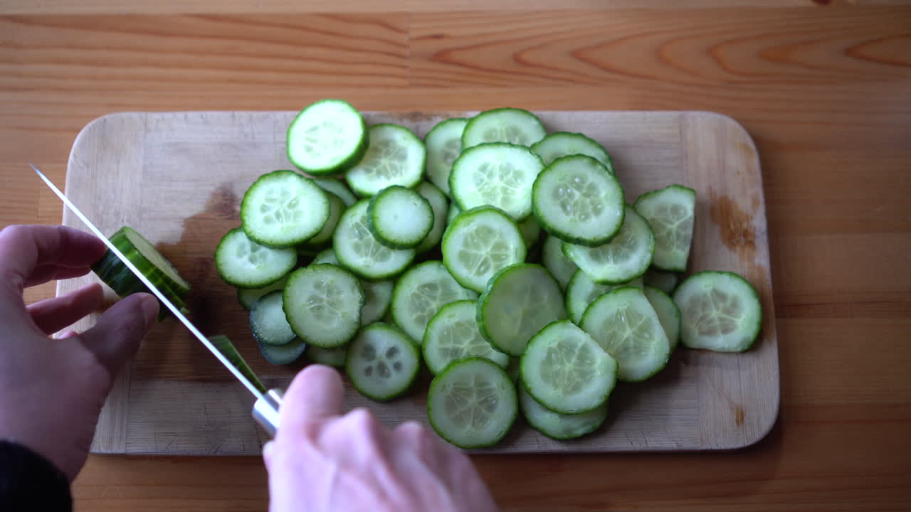 나무 보드를 자르고 오이를 자르는 남자 요리사
