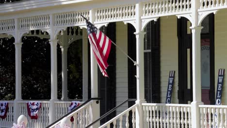 american flag waving on porch of classic southern plantation home