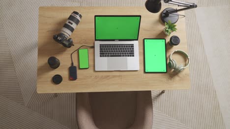 vista superior zoom en la toma de pantalla verde portátil, teléfono inteligente y tableta están al lado de la cámara en una mesa en el espacio de trabajo en casa