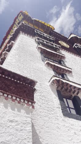 steep red and white walls of potala palace base angle in dramatic sunlight, vertical pan right
