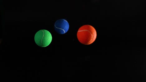 various colored tennis balls bouncing in darkness