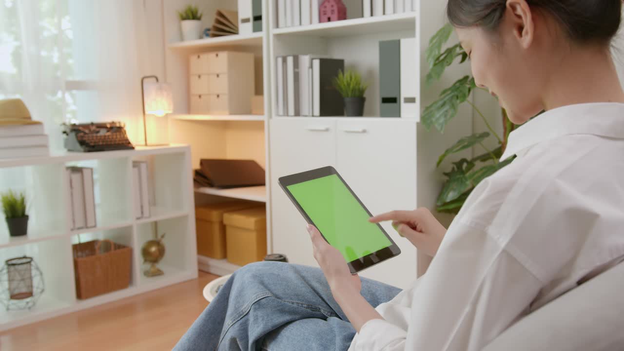 mujer sosteniendo una tableta digital con pantalla verde y dispositivo táctil navegando por internet.