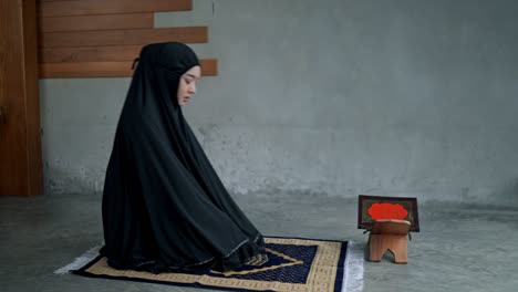 young muslim woman praying at home