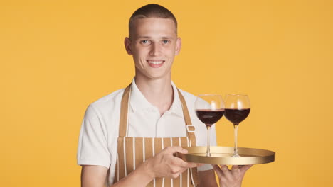 happy waiter serving two glasses of red wine