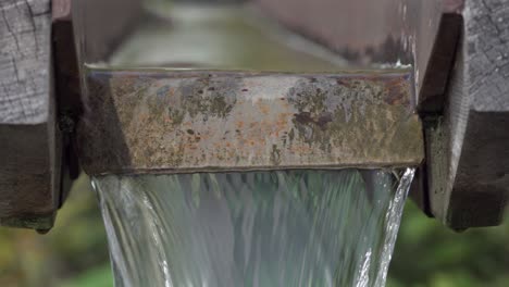 close-up of water flowing through a rustic wooden trough