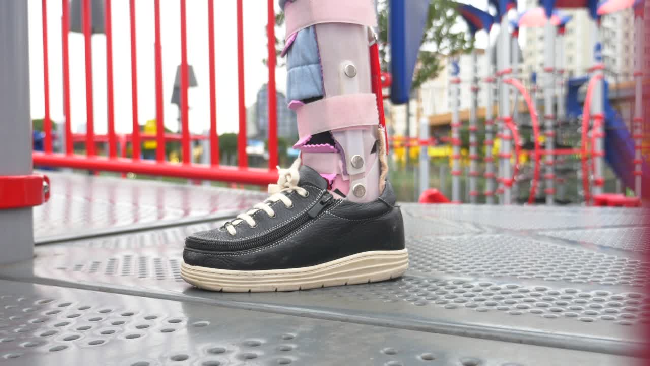 A young girl with a leg brace plays on a playground