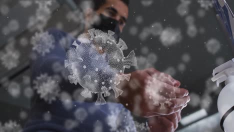 animation of covid-19 cells over middle eastern man wearing face mask applying hand sanitizer