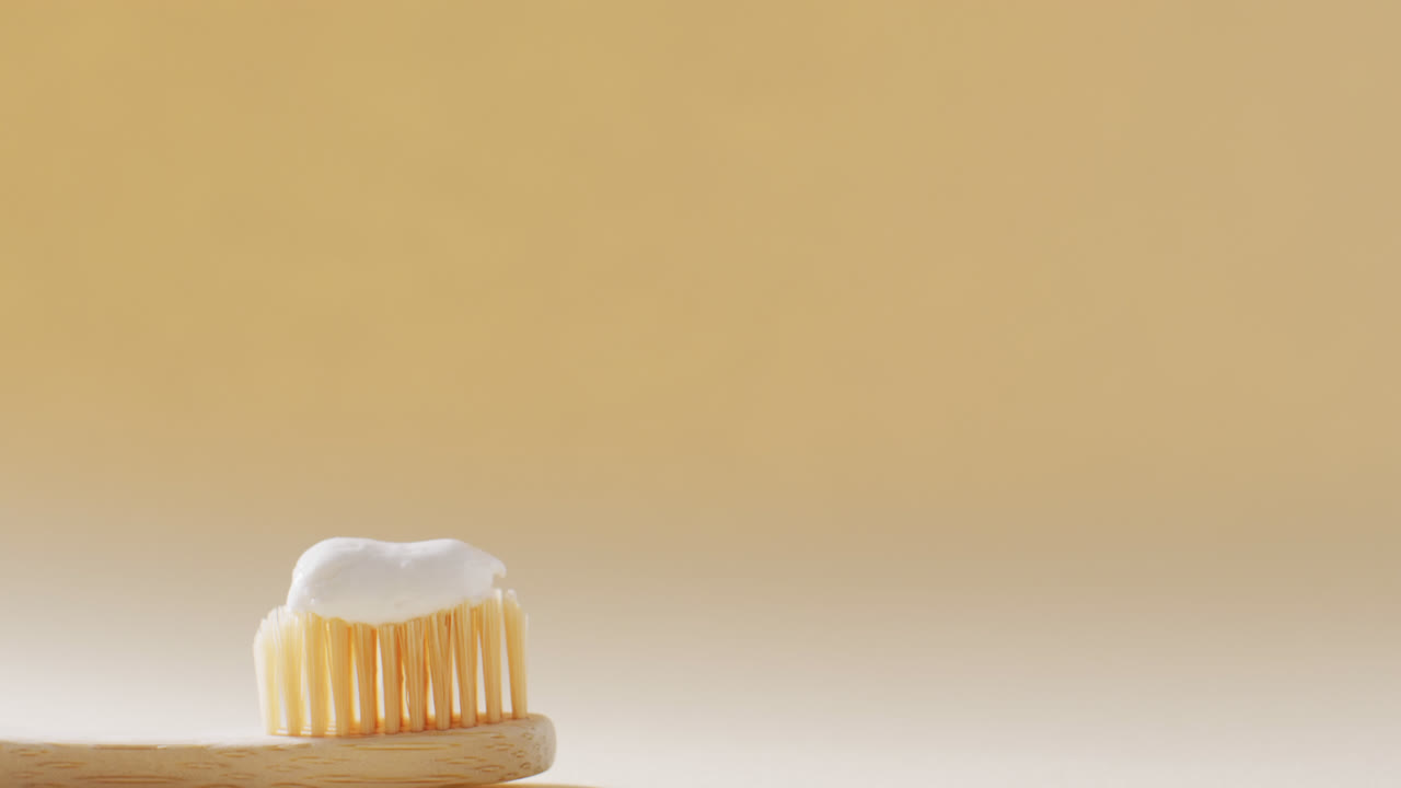 Close up of toothbrush with paste on beige background with copy space