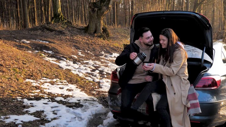 Caucasian couple having warm tea in a snowed forest.