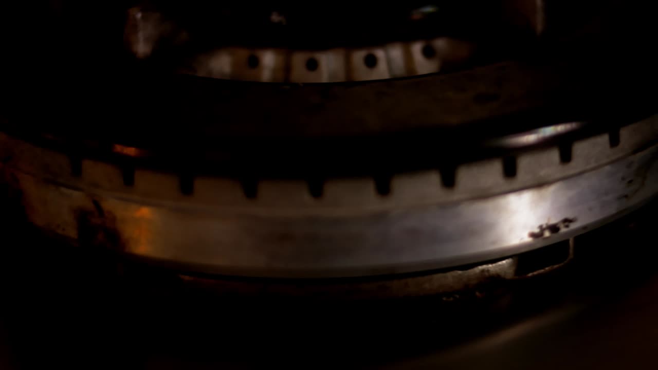 encendiendo la estufa de gas en fondo negro. quemador de cocina encendiendo. cerca de la llama. inflamación de gas natural en el quemador de la estufa, vista de cerca. quema de gas de una estufa de gasolina de cocina