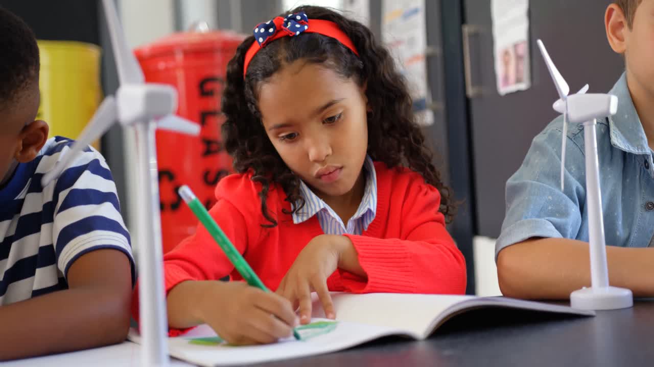 Front view of mixed-race schoolkids studying at desk in the classroom 4k