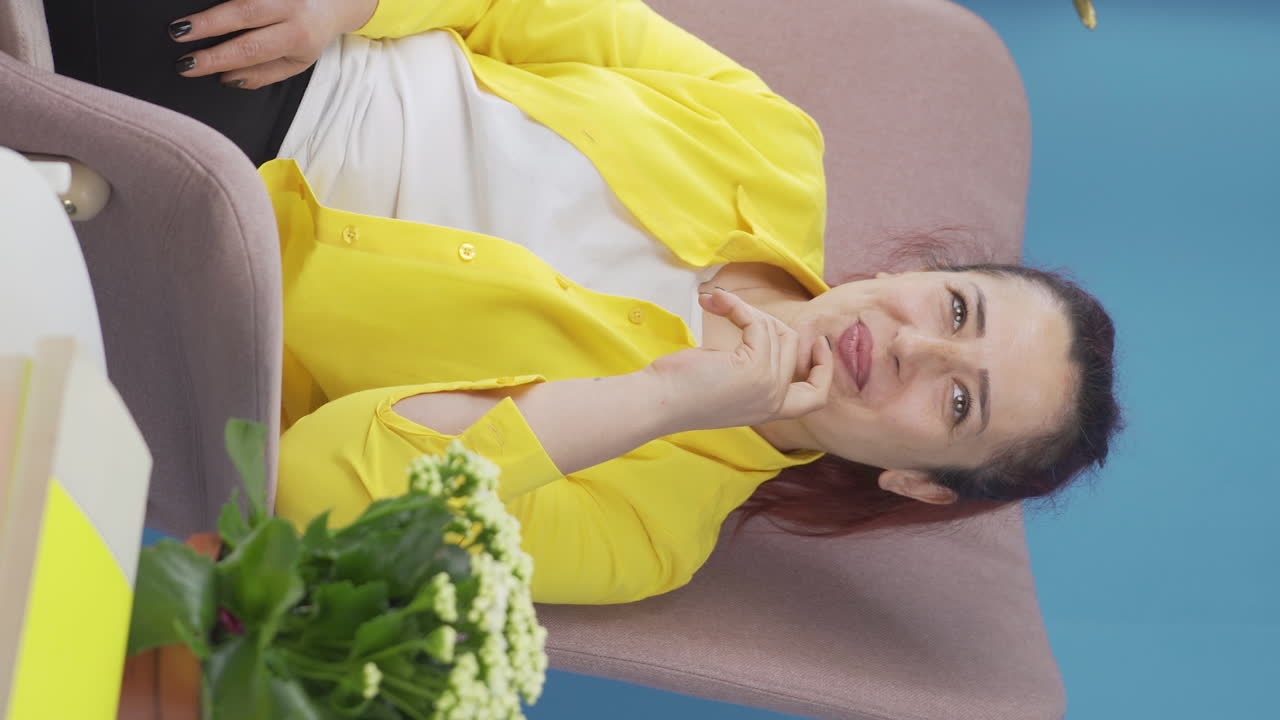 창문 앞의 수직 비디오에서 여자는 꿈을 꾸고 웃고 있습니다.