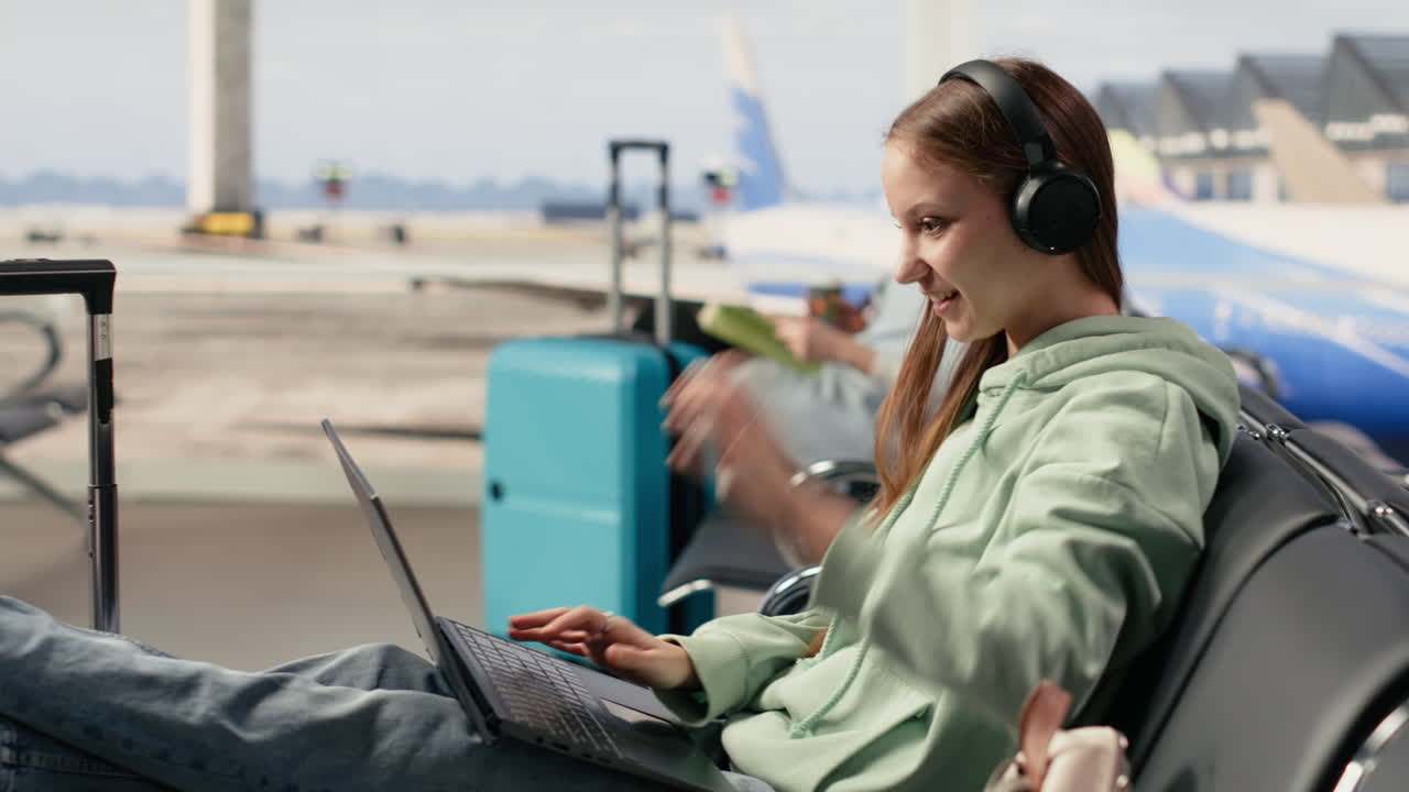 Mujer Joven Usando Portátil y Auriculares en la Zona de Espera del Aeropuerto