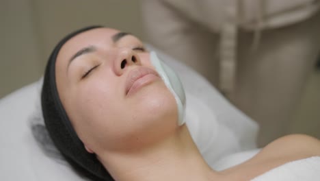 beautiful woman with facial mask at beauty salon