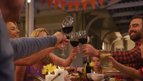 Three-generation-family-toasting-while-having-dinner-outdoors