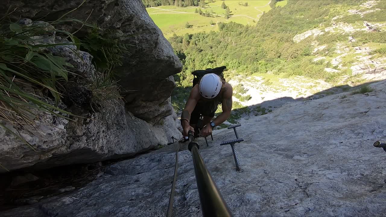 experiencia de turismo activo y extremo filmada por un hombre joven y en forma, escalando entre dos acantilados en lo alto de una montaña