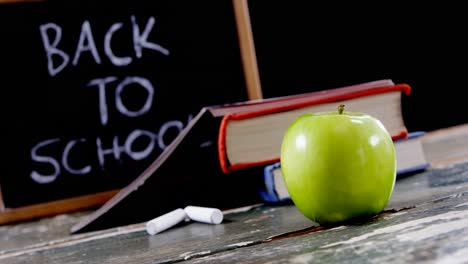 apple, book, chalk and slate on table