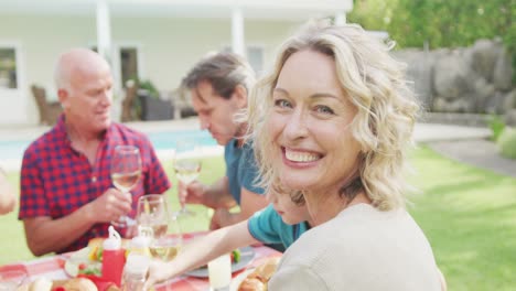 Portrait-of-happy-caucasian-woman-having-breakfast-with-family-in-garden