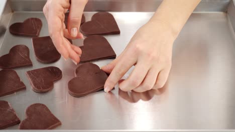 woman puts raw cookies on metal baking tray in kitchen