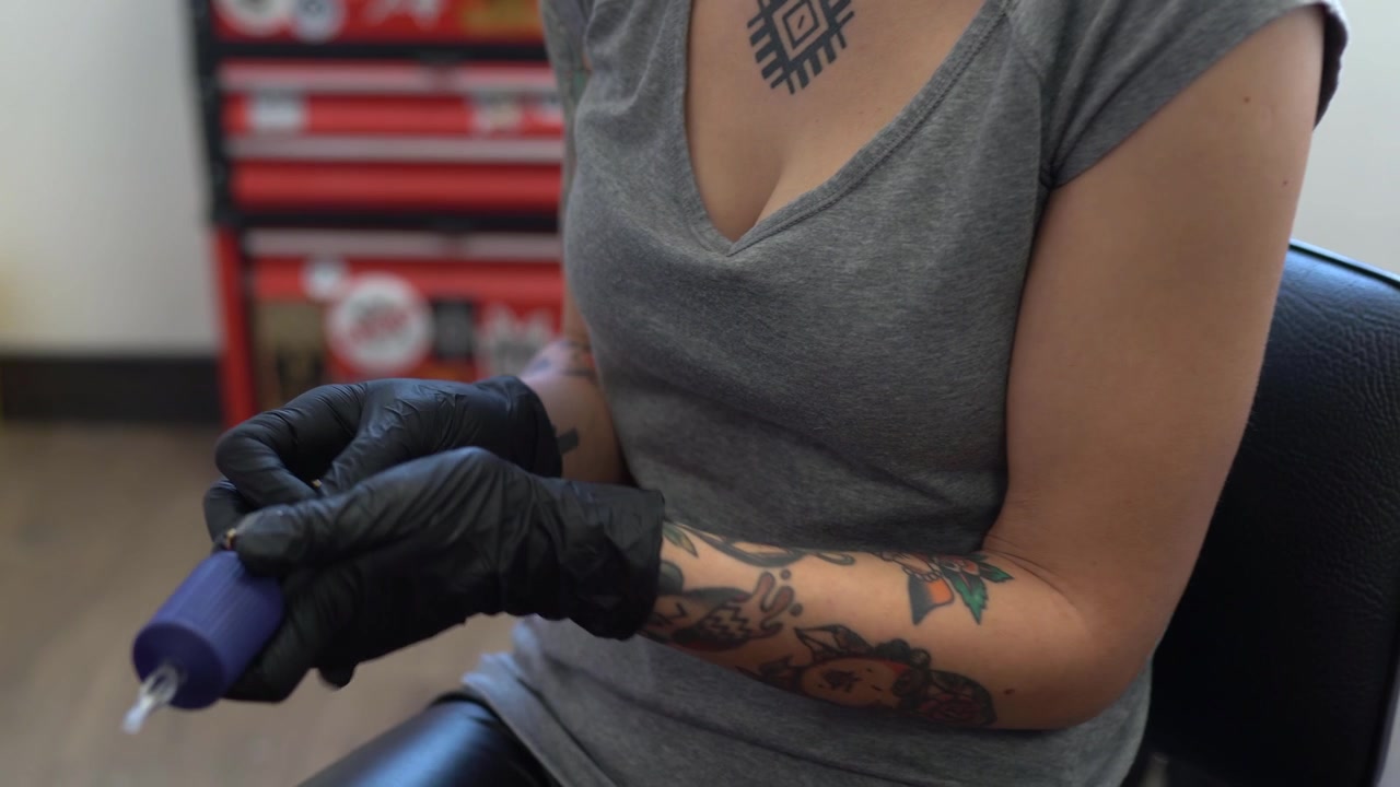 Tatuatrice che prepara la macchinetta per tatuaggi