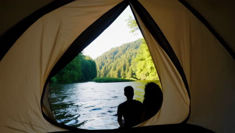 view from inside a tent by a serene river in the forest