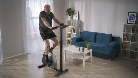 keeping fit and health for middle-aged people during self-isolation and pandemic of coronavirus man is training with exercycle