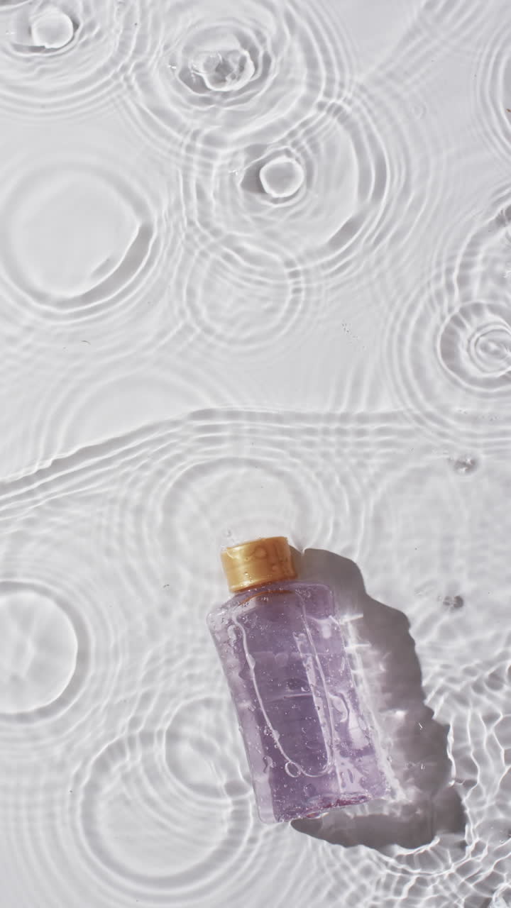 Video verticale di flacone di prodotto di bellezza nell'acqua con spazio per la copia su sfondo bianco