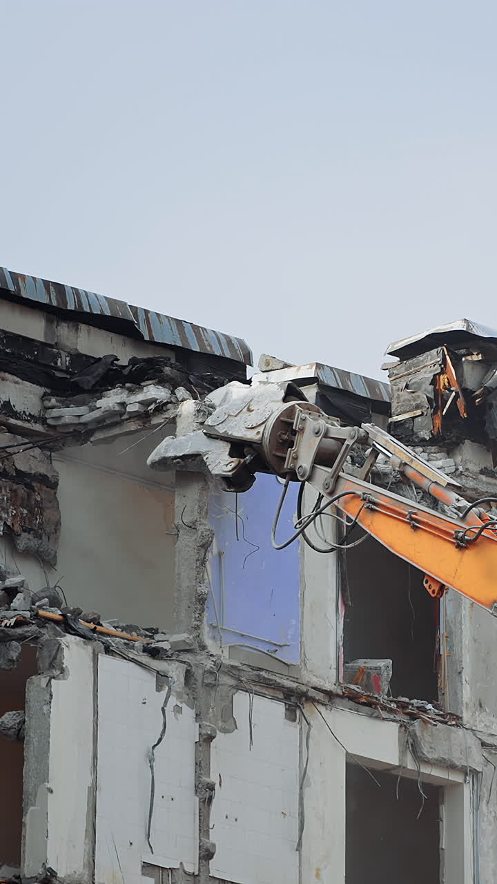 Special machine destroys a concrete house. Excavator machine with hydraulic crashers at demolition of the house.