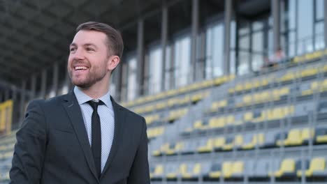 attractive young bearded businessman owner of football club in sports arena looking at clock attractive young bearded businessman owner of football club in sports arena looking at clock positive successful young man