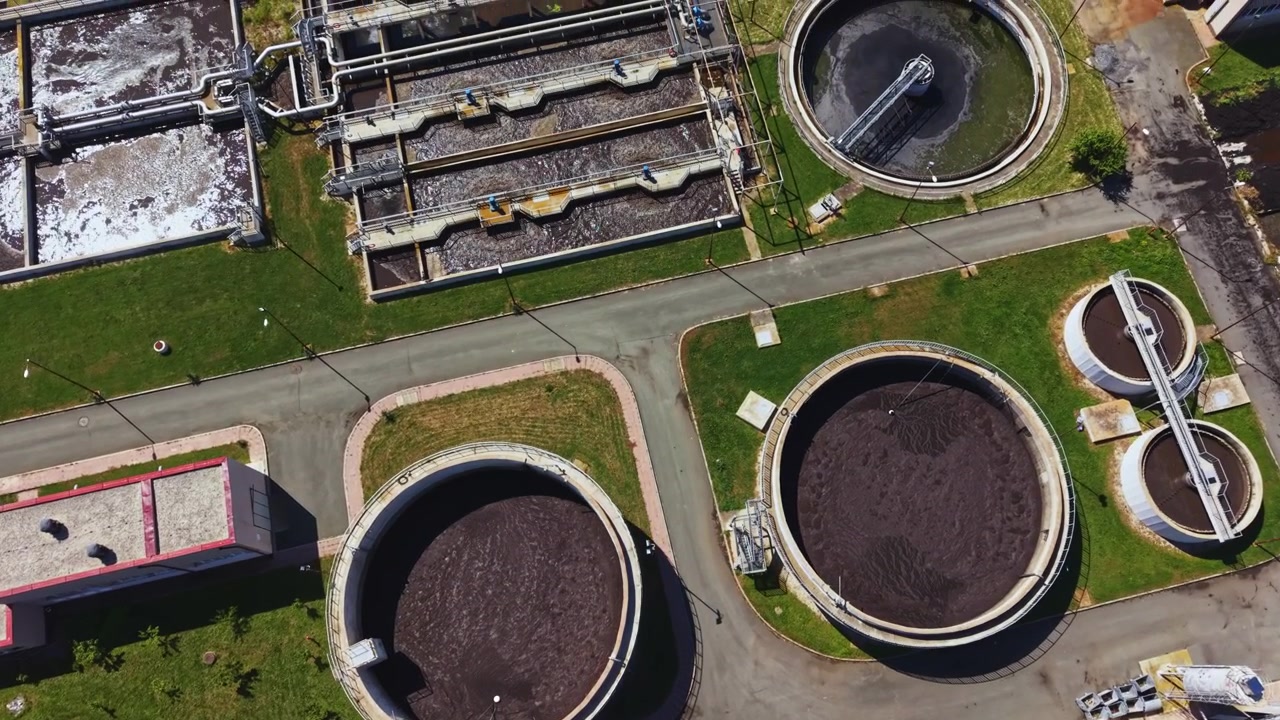 Aerial shot reveals layout and environment of treatment plant. Photograph displays geometric arrangements and infrastructure details of wastewater processing facility