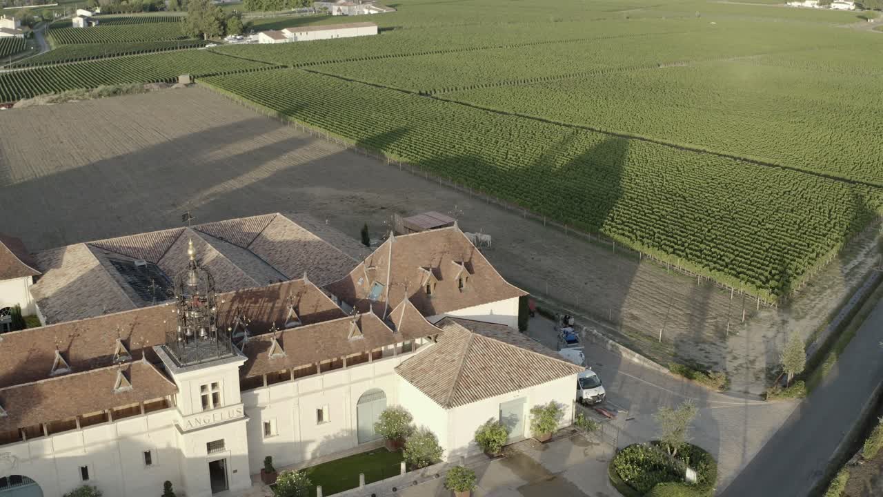 Château Angelus winery and vast vineyards at sunset, Saint-Émilion, Bordeaux region, France. Aerial drone orbiting