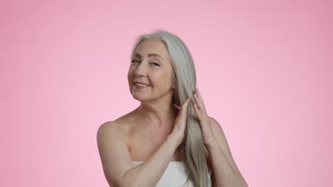 happy senior woman with healthy gray hair smiling on a pink background