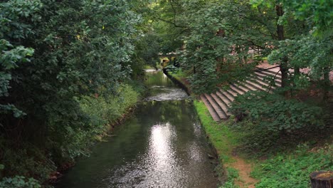 un río que fluye a través de una ciudad llena de vegetación en un verano caluroso