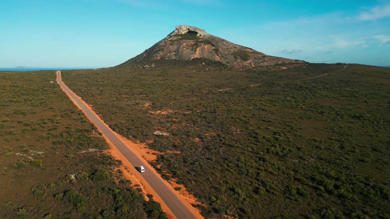 furgoneta conduciendo en una carretera recta en el parque nacional de cabo legrand con el pico francés en el fondo en un día soleado, esperance, australia occidental