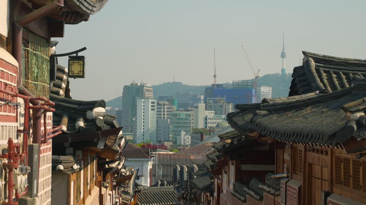 Bukchon Hanok Village, Seoul, presents a panoramic view of traditional Korean architecture, with its distinctive tiled roofs framing the distant modern cityscape and iconic N Seoul Tower - truck right