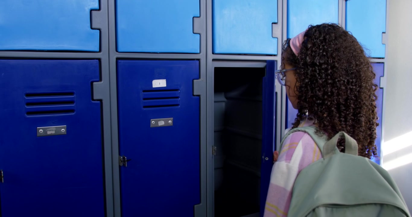 African American child approaching school lockers opening door turning key securing bag, copy space