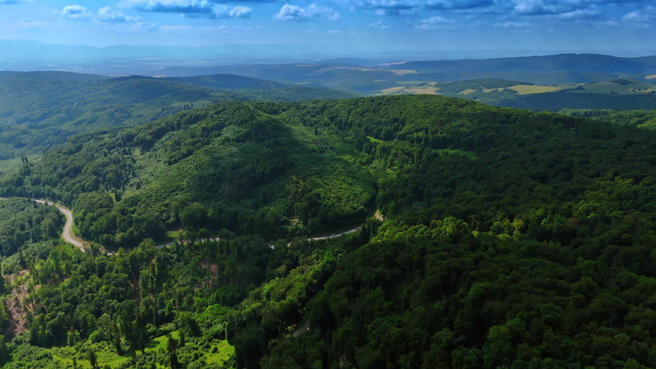 Lush green hills under a bright sky. Rolling hills covered in vibrant trees stretch under a clear blue sky, showcasing nature's beauty in the countryside
