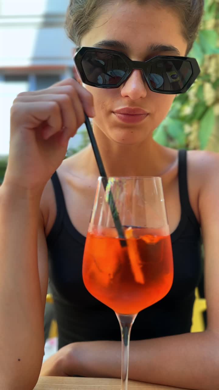 Frau genießt einen Aperol Spritz auf einer Café-Terrasse.
