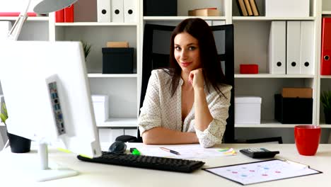 businesswoman leaning her chin and looking at camera in office