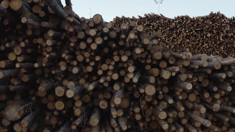 4k aerial shot moving sideways of large piles of timber, logs and wood at a factory in sweden