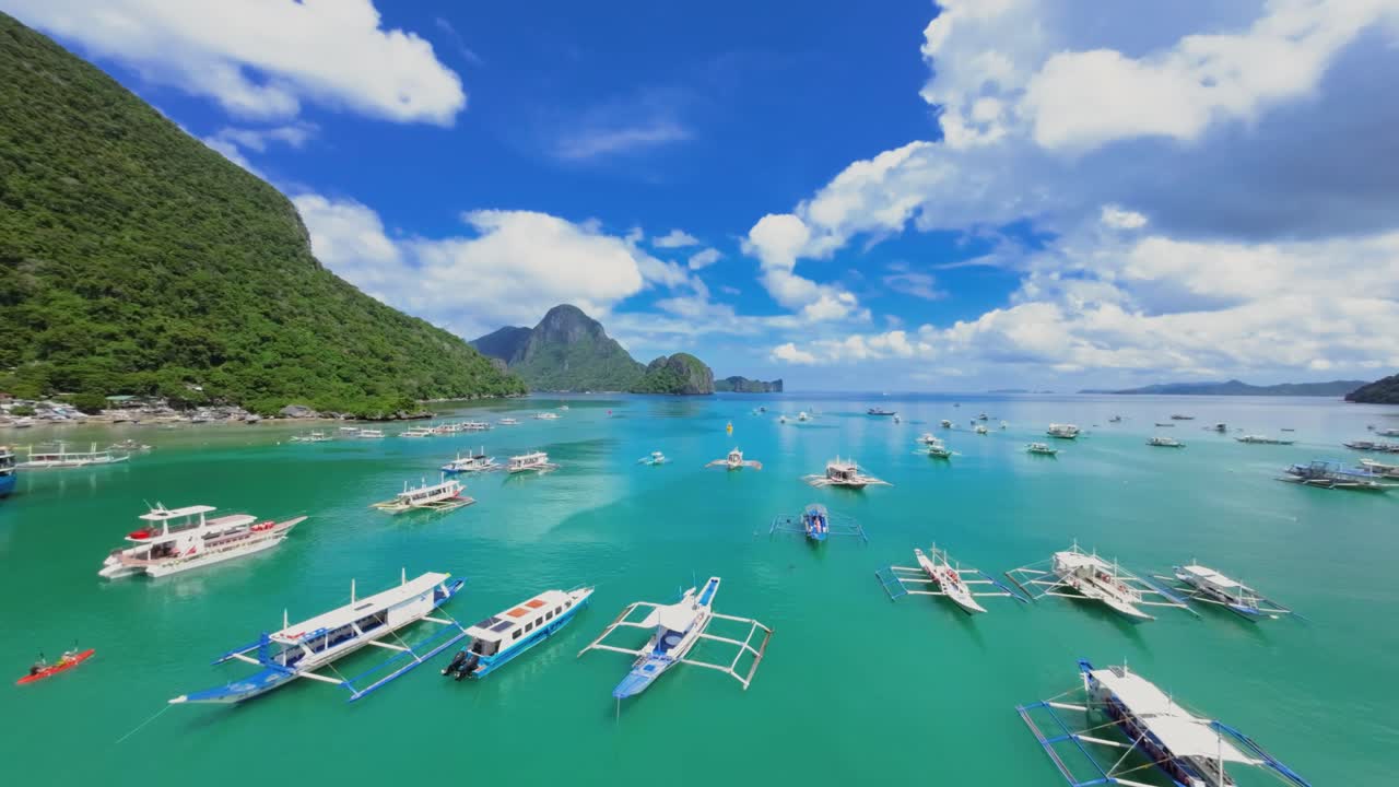 This mesmerizing aerial image captures the pristine turquoise waters of El Nido, Palawan, adorned with traditional Philippine outrigger boats known as "bancas."