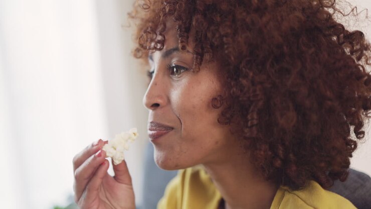 Woman eating popcorn while watching tv at home