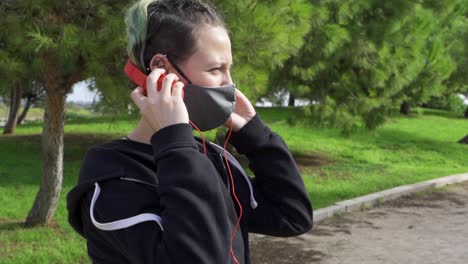 Woman-listening-to-alternative-music-taking-off-headphones-in-the-park
