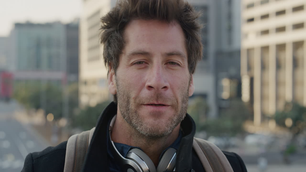 retrato de un joven atractivo corriendo con la mano a través del cabello disfrutando de un estilo de vida urbano relajado viajando en una ciudad ventosa al atardecer en cámara lenta