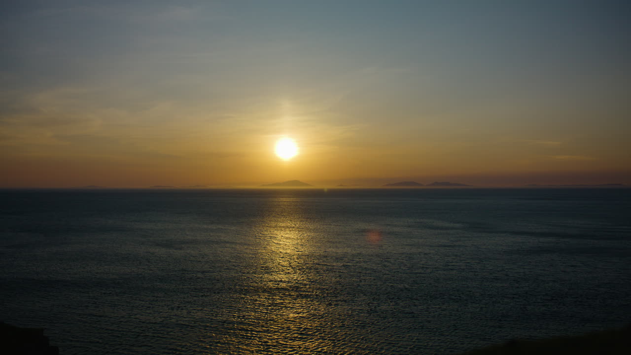 Golden sunset over calm sea with warm hues and serene atmosphere