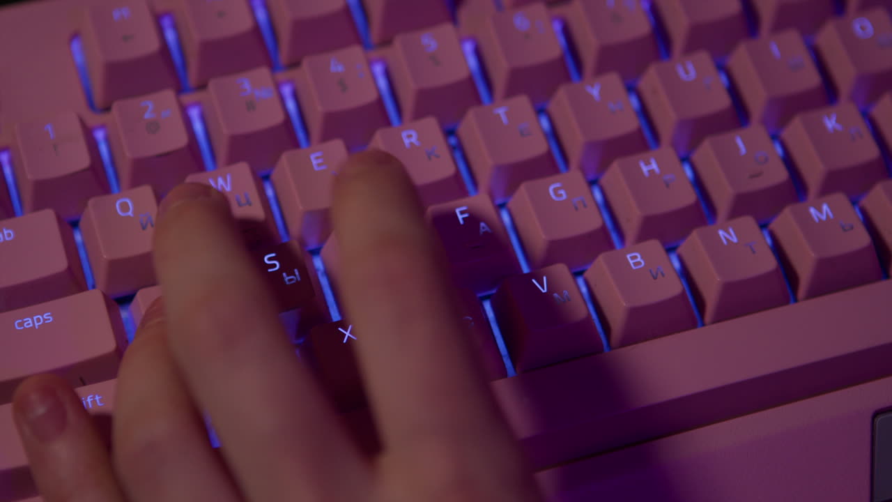 Hand Typing on a Pink Illuminated Keyboard