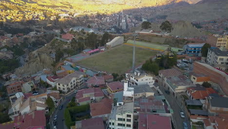 Aerial-view-of-cable-cars-traveling-over-a-football-field-in-La-Paz,-Bolivia